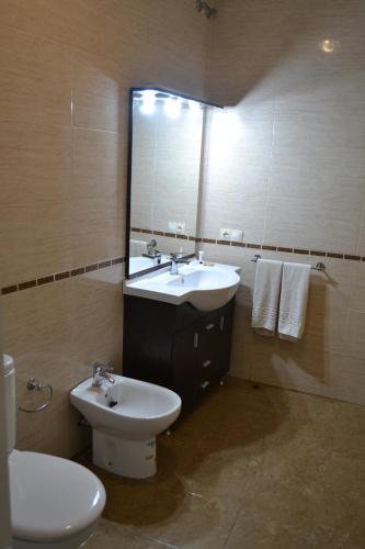 a bathroom with a sink and a toilet and a mirror at Ruralis Altozano in Montánchez