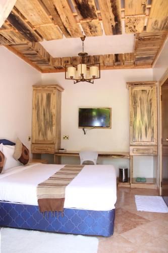 1 dormitorio con 1 cama y TV en la pared en Sahara Gardens-Kericho, en Kericho
