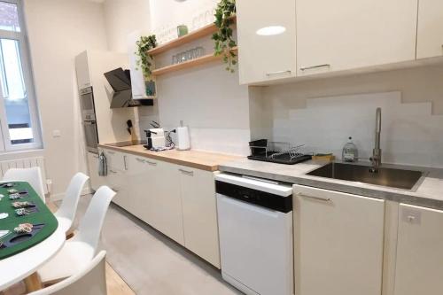 a kitchen with white cabinets and a sink and a table at L'As d'Aubert - 8 pers - Centre in Arras