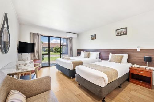 a hotel room with two beds and a couch at Auckland Airport Easy Hotel in Auckland