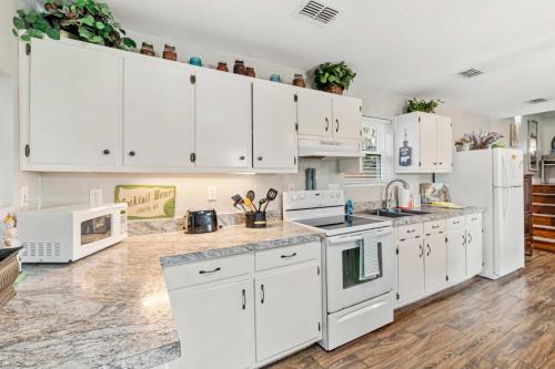 a kitchen with white cabinets and white appliances at Beach Barn - 5min to Pcola Beach , Full Kitchen in Gulf Breeze