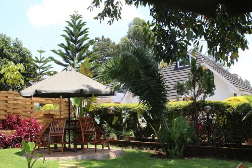 a table and chairs with an umbrella in a garden at Sahara Gardens-Kericho in Kericho