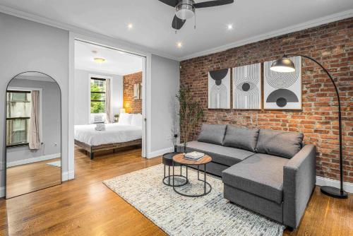 a living room with a couch and a brick wall at Modern Manhattan Retreat Near Central Park in New York
