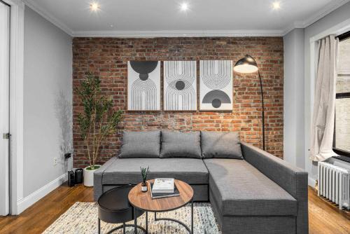 a living room with a couch and a brick wall at Modern Manhattan Retreat Near Central Park in New York