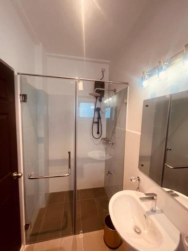 a bathroom with a glass shower and a sink at Santorini Transit hotel in Negombo
