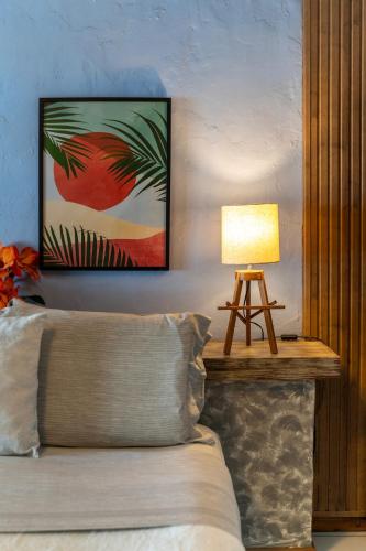 a bedroom with a bed and a table with a lamp at Pousada dos Gravatás in Búzios