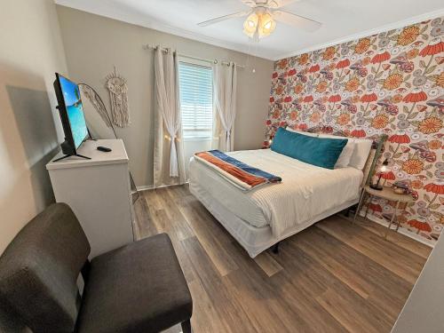 a bedroom with a bed and a tv and a chair at Portabella Paradise in Carolina Beach