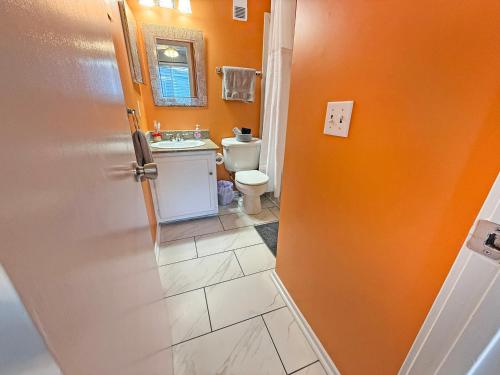 an orange bathroom with a sink and a toilet at Portabella Paradise in Carolina Beach