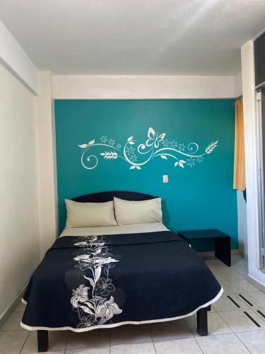 a bed with a blue wall with a lizard on it at Hotel MERLI in Asunción Nochixtlán