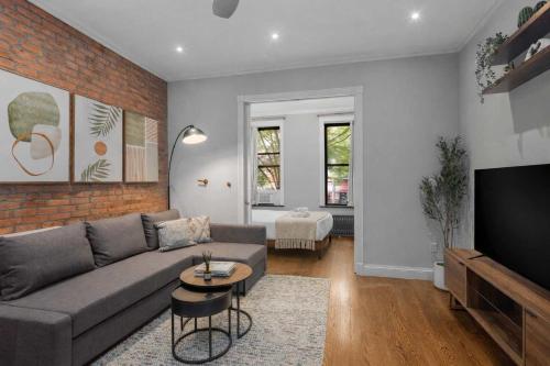 a living room with a gray couch and a brick wall at Chic NYC Retreat by Central Park in New York