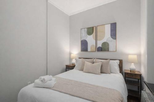 a white bedroom with a white bed with two lamps at Chic NYC Retreat by Central Park in New York