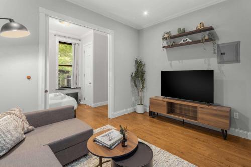 a living room with a couch and a flat screen tv at Chic NYC Retreat by Central Park in New York