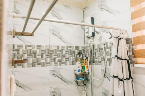 a shower in a bathroom with white marble tiles at Rubi's House in Ilayang Talim