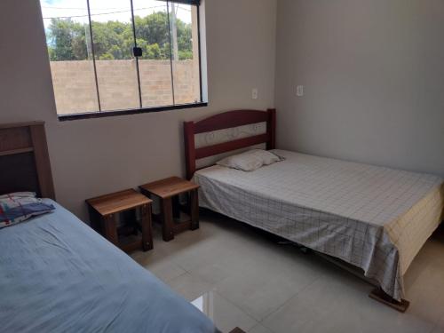a bedroom with two beds and a window at Área de Lazer Portal da Canastra in Delfinópolis