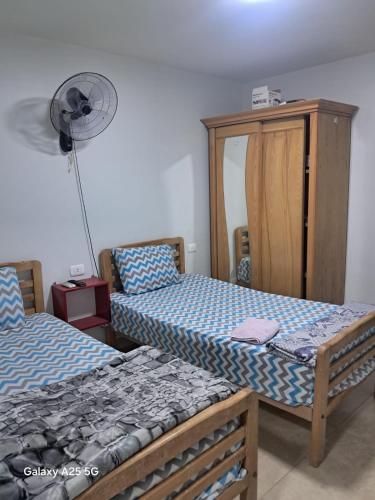 a bedroom with two beds and a fan at Hayat Pyramids House DBL 59S in ‘Ezbet `Abd el-Ḥamîd