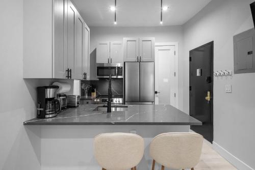 a kitchen with white cabinets and a counter with two chairs at Modern Nolita Hideaway in New York