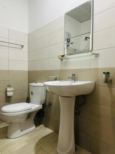 a bathroom with a toilet and a sink and a mirror at Kandyan Gate Homestay in Kandy