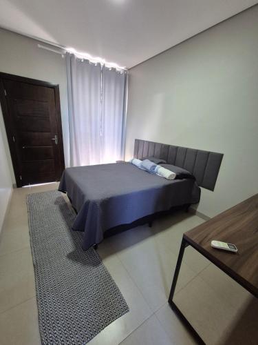 a bedroom with a bed and a table and a window at Apartamento Centro 02 in Vilhena