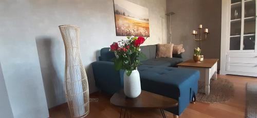 a living room with a blue couch and a vase of flowers at Haus am Bach in Miehlen