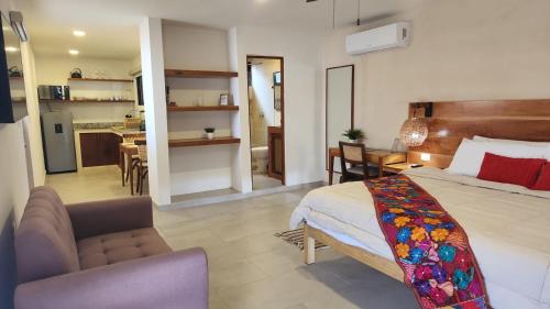 a bedroom with a bed and a couch and a kitchen at Modern loft with AC near Paseo Montejo - El Rosal in Mérida