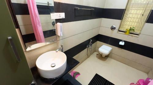 a bathroom with a white toilet and a sink at Swasth The Riviera Lovedale in Nilambūr