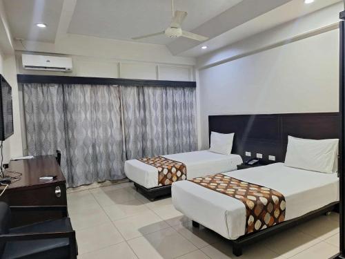una camera d'albergo con due letti e una tv di Hotel Takia a Labasa