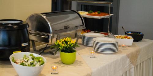 a table with plates and bowls of food and flowers at Hotel Zorza in Kołobrzeg