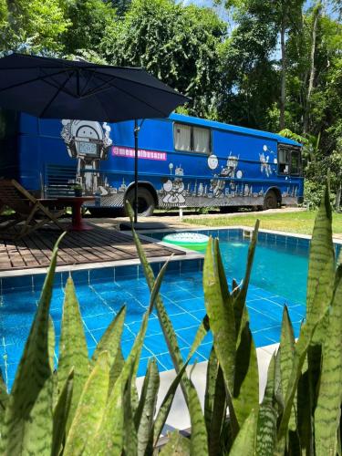 an rv parked next to a pool with an umbrella at Ônibus Azul - Experiência de Hospedagem em Domingos Martins in Domingos Martins