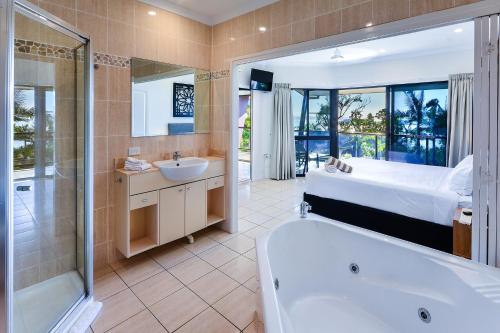 a bathroom with a tub and a bed and a sink at Hamilton Island Holiday Homes in Hamilton Island