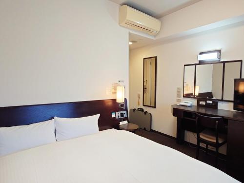 a hotel room with a bed and a desk at Hotel Route-Inn Yurihonjo in Yurihonjo