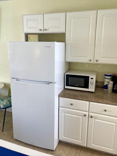 a white kitchen with a refrigerator and a microwave at Beachgate Condo Suites and Hotel 436 condo in Port Aransas