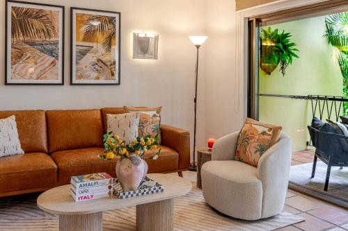 a living room with a couch and a table and a chair at Let's Get Tropical, Located In The Heart Of Town, 2 King Beds, 2 Pools, 2 Bathrooms in Port Douglas
