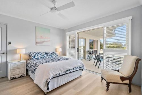 a bedroom with a bed and a chair and a window at Whale Point in Yaroomba