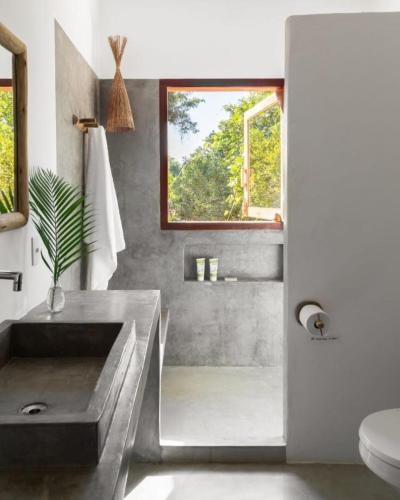 a bathroom with a concrete sink and a window at Casa Pini - Condomínio Altos de Trancoso, próxima ao Quadrado in Trancoso