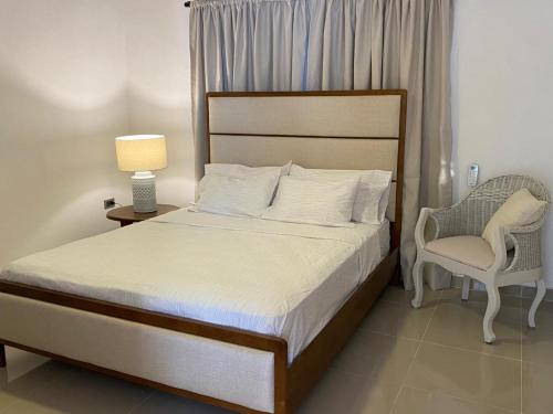 a bedroom with a bed and a chair and a lamp at Apartamento San Pedro Colonial in San Pedro de Macorís