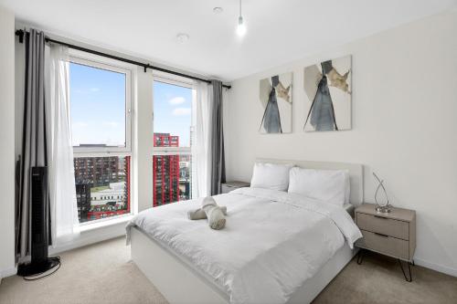a white bedroom with a large white bed and two windows at Penthouse with O2 Arena View, Free Parking & Portable AC in London