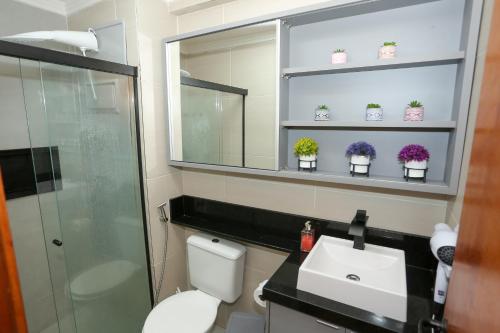 a bathroom with a toilet and a sink and a mirror at Flat Rosarinho - Confortável e Super Completo in Recife