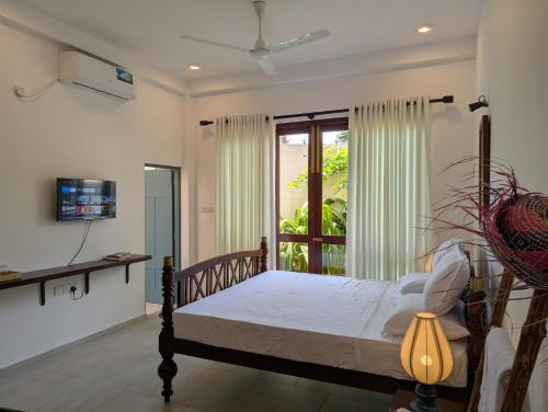 a bedroom with a bed and a window at Villa Sethoskai -100m to Beach in Ambalangoda