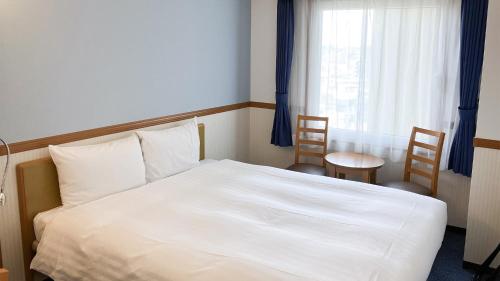 a bedroom with a white bed and a window at Toyoko Inn Naha Omoromachi Ekimae in Naha