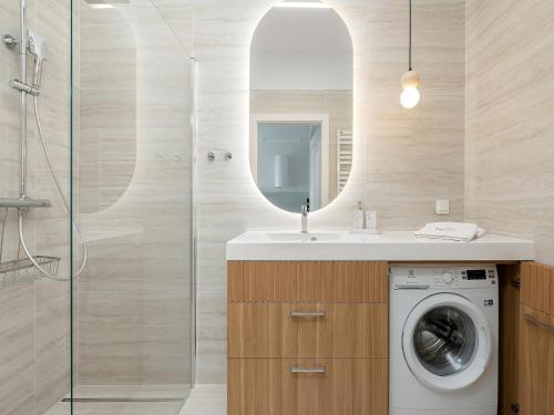 a bathroom with a washing machine and a mirror at Comfortable apartment, right on the beach in Niechorze