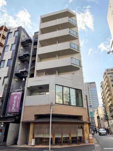 a tall building with balconies on a city street at BALCOM STAY Hiroshima Otemachi in Hiroshima