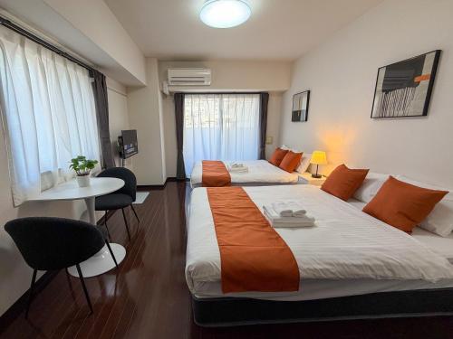 a hotel room with two beds and a table and chairs at BALCOM STAY Hiroshima Otemachi in Hiroshima