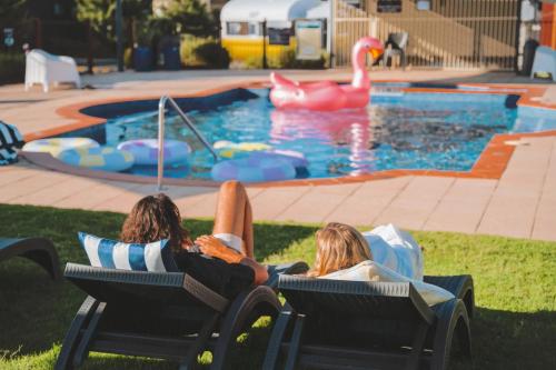 two people laying in lawn chairs in front of a pool at BIG4 Tasman Holiday Parks - Bendigo in Bendigo