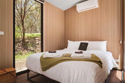 a bedroom with a large bed with a window at Maroota Greens X by Tiny Away in Maroota