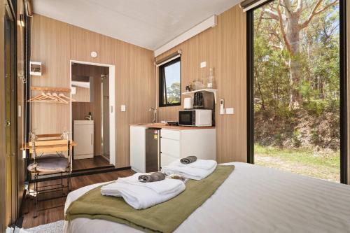 a bedroom with a large bed with towels on it at Maroota Greens X by Tiny Away in Maroota