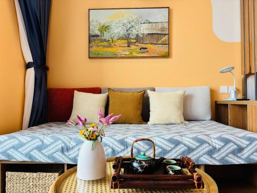 a room with a bed and a table with a vase of flowers at Măng Homestay in Kim Quan