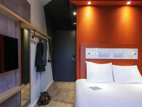 a bedroom with a white bed and an orange wall at ibis budget Rotterdam The Hague Airport in Rotterdam