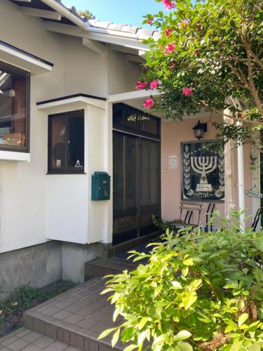 a house with a black door and some pink flowers at ＯＫＵＮＯ ＩＥ in Oshima