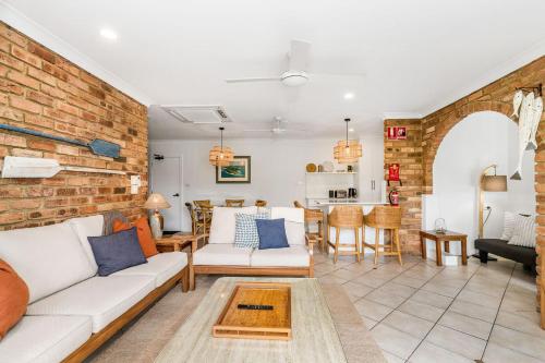 a living room with a white couch and a brick wall at Atlantis 6 - 70 Lawson Street in Byron Bay