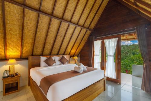 a bedroom with a large bed and a window at La Rise Penida Cottage in Nusa Penida